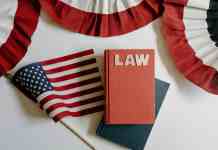 The History of the American Constitution red and blue notebook beside american flag