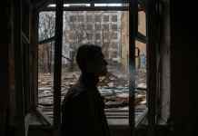 a man standing by the window of an abandoned building