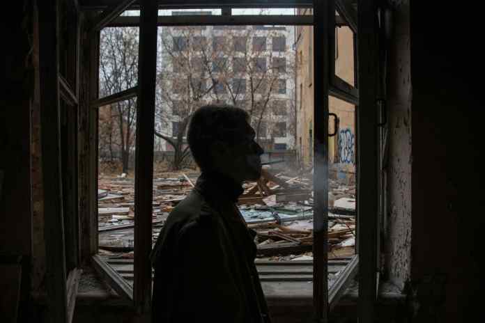 a man standing by the window of an abandoned building