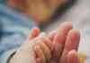 tender baby hand holding adult finger in focus